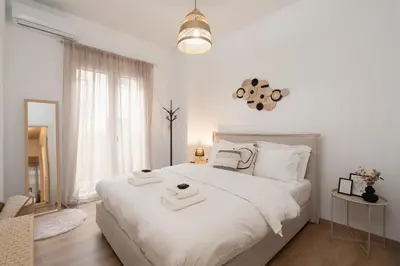 a white bedroom with a white bed with towels on it at My Happy Greek Home in Athens