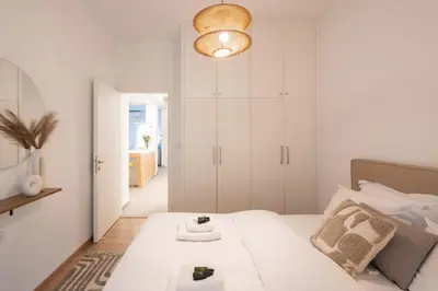 a white bedroom with a large bed and a light fixture at My Happy Greek Home in Athens