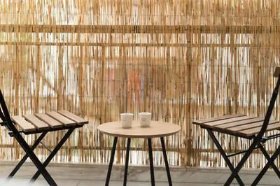 two chairs and a table in front of a bamboo wall at My Happy Greek Home in Athens