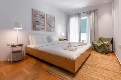 a bedroom with a large bed and a large window at Zen Vouliagmeni Beach Apartment in Athens