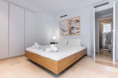 a white bedroom with a large bed in a room at Zen Vouliagmeni Beach Apartment in Athens