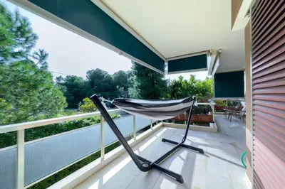 a hammock on the balcony of a house at Zen Vouliagmeni Beach Apartment in Athens