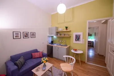 a living room with a blue couch and a kitchen at Garden-studio in a mansion-Athens-Chalandri center in Athens
