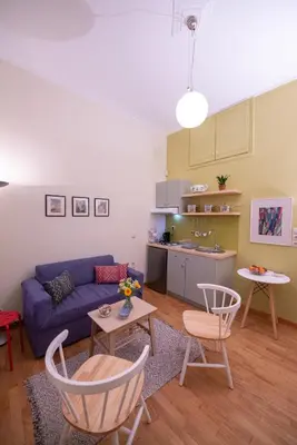 a living room with a blue couch and a kitchen at Garden-studio in a mansion-Athens-Chalandri center in Athens