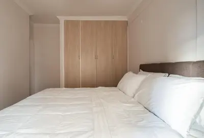 a bed with white sheets and a wooden cabinet at Erechthiou 15 Koukaki Apartment by Athens Concept Residences in Athens