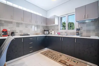 a kitchen with black cabinets and a rug on the floor at Oikia in Athens