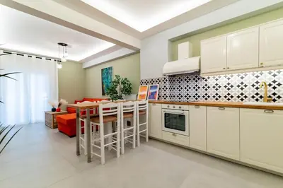 a kitchen with white cabinets and a table with chairs at Psirri Urban Chic in Athens