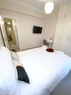 a bedroom with a large white bed with a flat screen tv at MediTerra Stay Athens City Center in Athens
