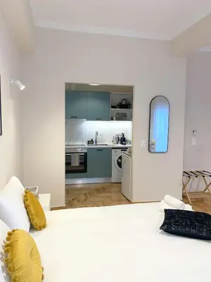 a white room with a large bed and a kitchen at MediTerra Stay Athens City Center in Athens