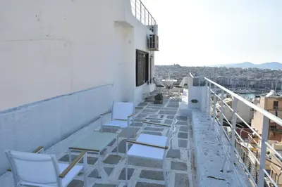 a row of white chairs sitting on a balcony at Modern Apartment with Stunning Piraeus Views in Piraeus