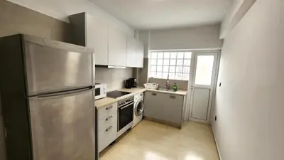 a kitchen with a stainless steel refrigerator and white cabinets at Grec Maison Piraeus by GrecCollection in Piraeus