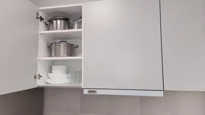 a white kitchen cabinet with dishes on it at Grec Maison Piraeus by GrecCollection in Piraeus