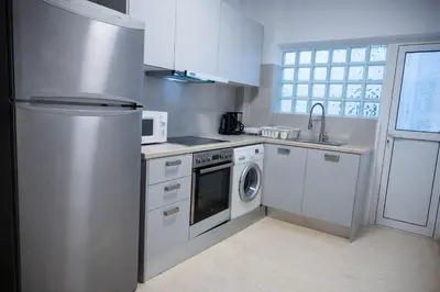 a kitchen with white cabinets and a washer and dryer at Grec Maison Piraeus by GrecCollection in Piraeus