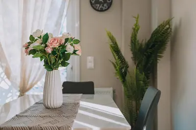 a white vase with pink flowers on a table at Brand New Building Deluxe Apartments With Parking Nearby Train in Athens