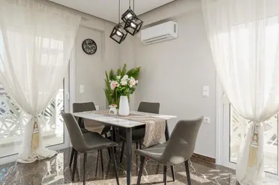 a dining room with a table and chairs and a clock at Brand New Building Deluxe Apartments With Parking Nearby Train in Athens