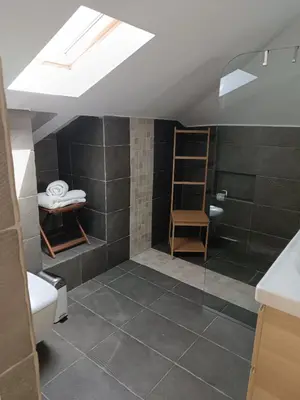 a bathroom with a sloped ceiling with a glass shower at ATH Airport, Loft in Painia in Paianía