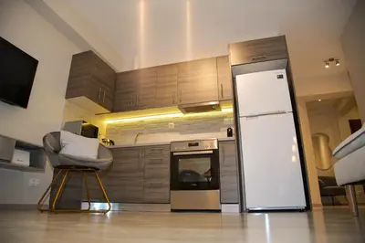 a kitchen with a refrigerator and a chair in it at Sunset Haven Piraeus in Piraeus