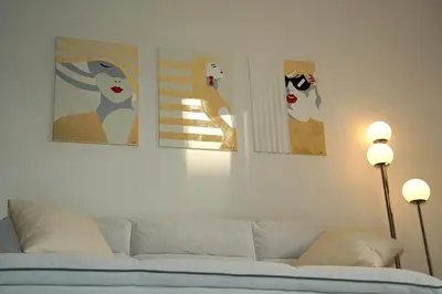 three paintings on a wall above a couch at Sunset Haven Piraeus in Piraeus