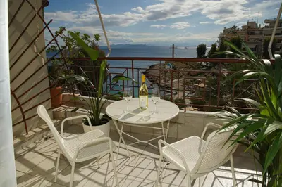 a table and chairs on a balcony with a bottle of wine at Sunset Haven Piraeus in Piraeus