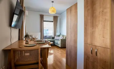 a kitchen with a table and a living room with a couch at Acropolis Penthouse Project in Athens