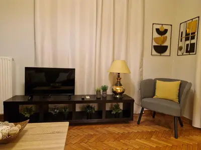a living room with a television and a chair at SYGGROU - ONASSIO and REA Hospitals - 1bdr APT - sleep 2-4p in Athens