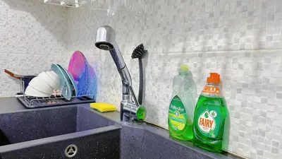 a kitchen counter with a sink with cleaning products on it at LiI\u7684\u516c\u5bd3\u79bb\u6d771\u5206\u949f Ps5 macPC sony\u7535\u89c6 \u8212\u9002\u5927\u5e8a\u8bb0\u5fc6\u5e8a\u57ab \u6e38\u620f\u5f71\u89c6\u4f11\u95f2\u516c\u5bd3 \u9152\u5e97\u7528\u54c1 in Piraeus