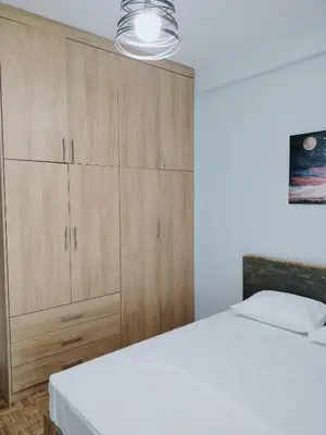 a bedroom with a white bed and wooden cabinets at MYKALI's COZY APARTMENT in Athens