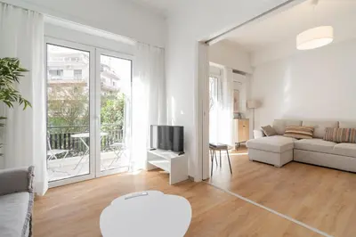 a white living room with a couch and a tv at City Center Balcony Escape in Athens
