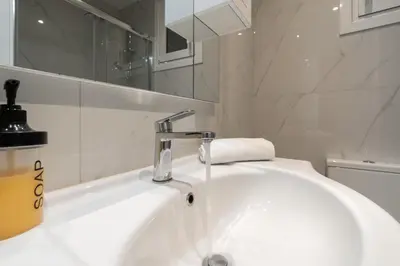a white bathroom with a sink and a mirror at City Center Balcony Escape in Athens