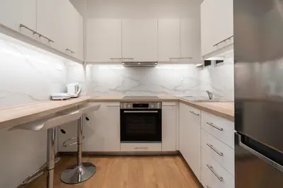a kitchen with white cabinets and a black appliance at City Center Balcony Escape in Athens