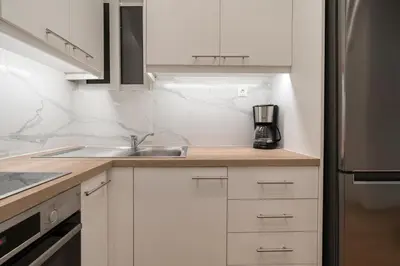 a kitchen with white cabinets and a sink at City Center Balcony Escape in Athens