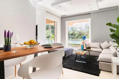 a living room with a table and white chairs at Eclipse Riviera Cosy in Athens