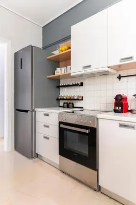 a kitchen with white cabinets and a stainless steel refrigerator at Eclipse Riviera Cosy in Athens