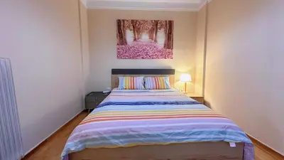 a bedroom with a bed and a painting on the wall at Yu\u7684\u516c\u5bd3 \u5730\u94c1\u9644\u8fd12\u4e2a\u5927\u5e8a\u623f\u7535\u7ade\u6e38\u620f\u4f11\u95f2\u9152\u5e97\u516c\u5bd3\u5546\u4e1a\u8857\u8d85\u5e02\u8f7b\u8f68\u6e2f\u53e3\u673a\u573a\u76f4\u8fbe in Piraeus