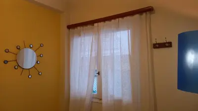 a window with a white curtain and a mirror at Spacious apartment near Acropolis in Athens