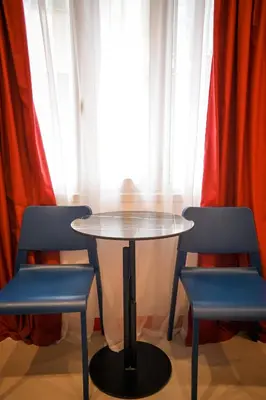 a table and two blue chairs in front of a window at Plaka Suite Next to Acropolis by Zeus Suites in Athens