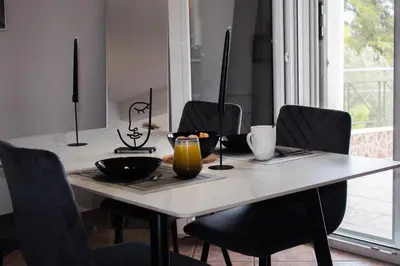 a dining room table with black chairs and a table with a bowl and a candle at EMVI APARTMENTS VI near airport in Vravrona