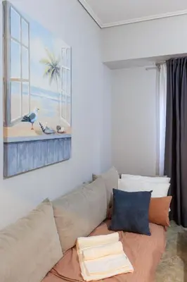a couch in a living room with a painting on the wall at AIOLOS HABITAT pagrati apartment ATHENS in Athens