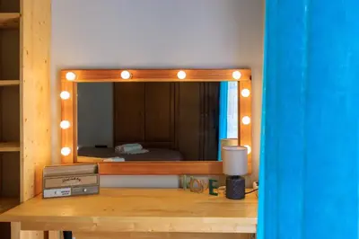 a mirror with lights on top of a wooden table at AIOLOS HABITAT pagrati apartment ATHENS in Athens