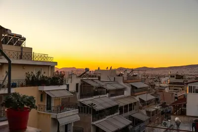 a view of a city at sunset with buildings at Urban cozy penthouse with city view in Athens