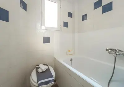 a bathroom with a toilet and a tub and a window at Urban cozy penthouse with city view in Athens