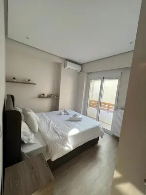 a bedroom with a white bed and a large window at Stylish Condo Nearby Acropolis & Metro in Athens