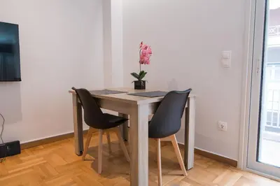 a dining room table with two chairs and a vase of flowers at Arie Central Apartments by Live & Travel in Athens