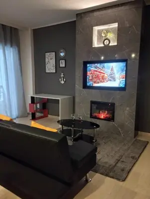 a living room with a black couch and a fireplace at Elegant Minimalistic Downtown Apartment! in Athens