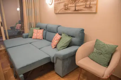 a living room with a blue couch and a chair at Little Acropolis in Athens