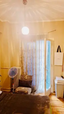 a bedroom with a bed with a curtain and a window at Quiet Arty Cosy Cool Flat Downtown in Athens