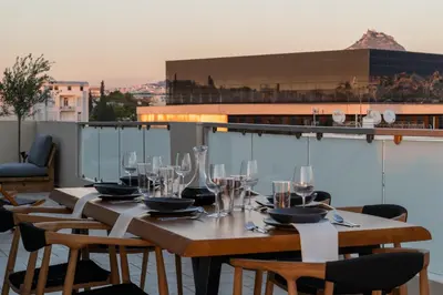 a table with wine glasses on top of a balcony at Elegant Skyline Penthouse Acropolis View 3BR 2BA in Athens