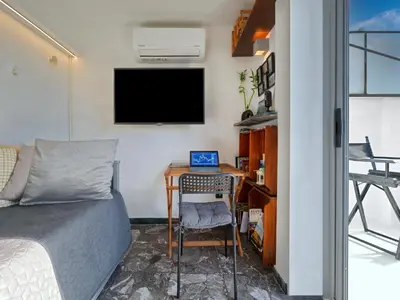 a bedroom with a bed and a desk with a laptop at Athens at your feet - Modern Loft with a view in Athens