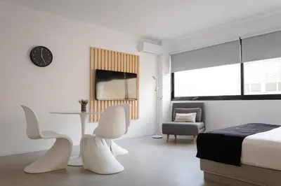 a white bedroom with a bed and a desk and chairs at Syntagma Serenity Suites in Athens