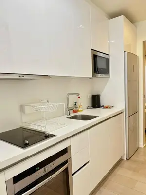 a white kitchen with a sink and a refrigerator at Elegant apartment in Kolonaki in Athens